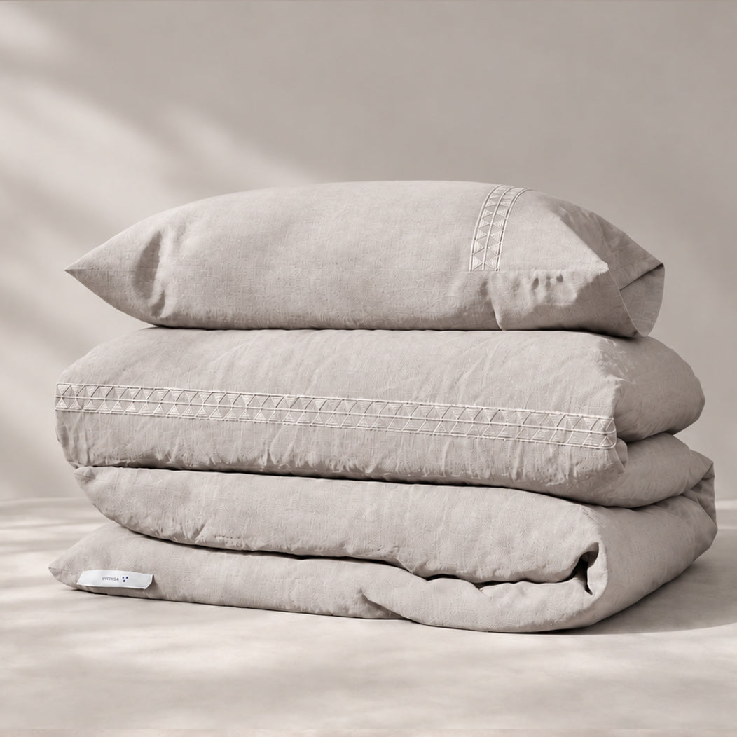 Funda Duvet Alba de lino misto bruma con bordado geométrico tono a tono y fundas de almohada, presentada doblada.