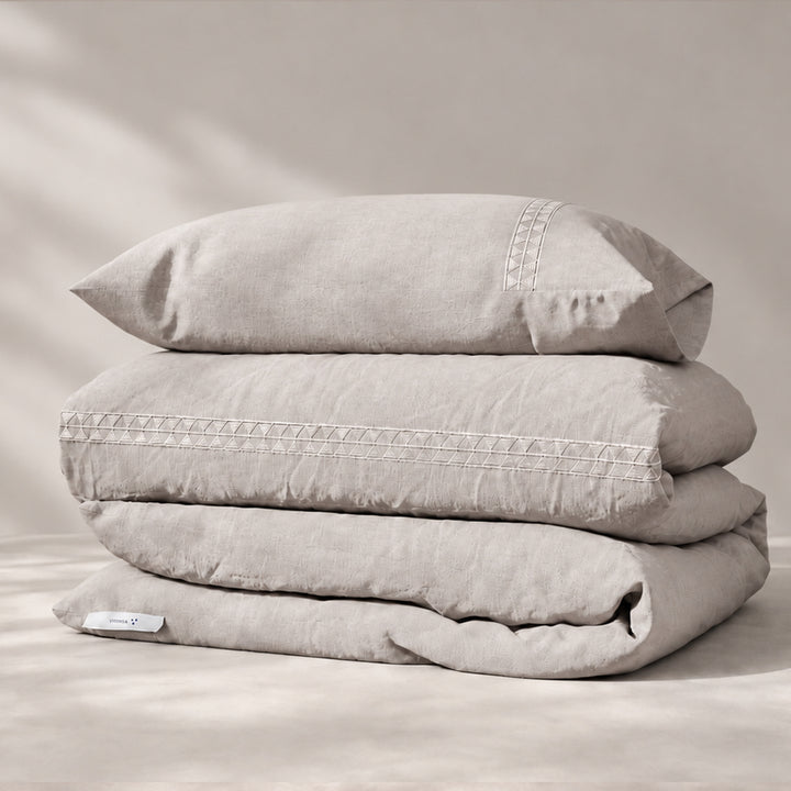 Funda Duvet Alba de lino misto bruma con bordado geométrico tono a tono y fundas de almohada, presentada doblada.