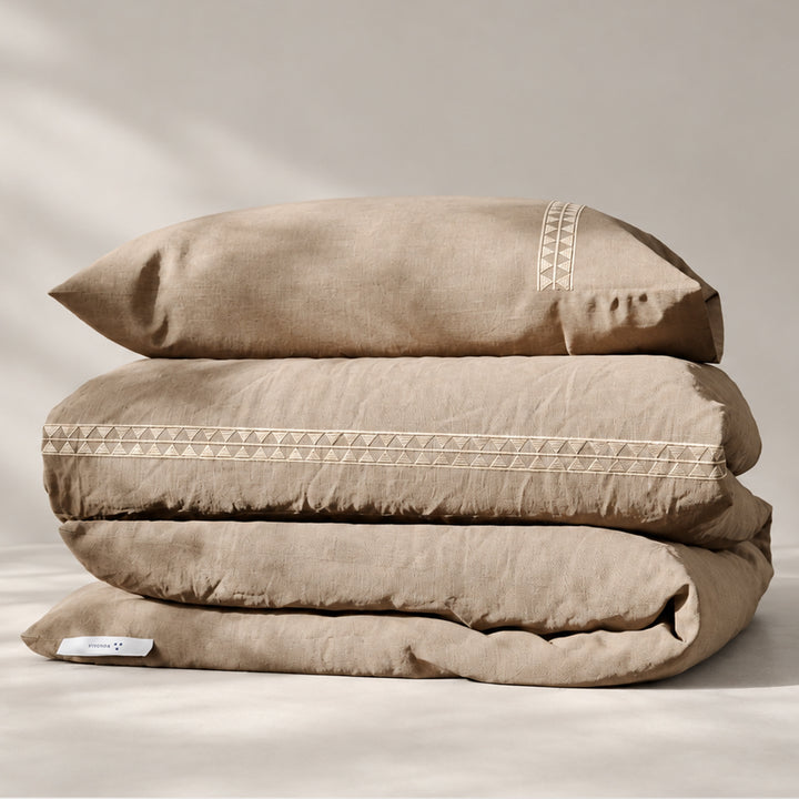 Funda Duvet Alba de lino misto natural con bordado geométrico tono a tono y fundas de almohada, presentada doblada.