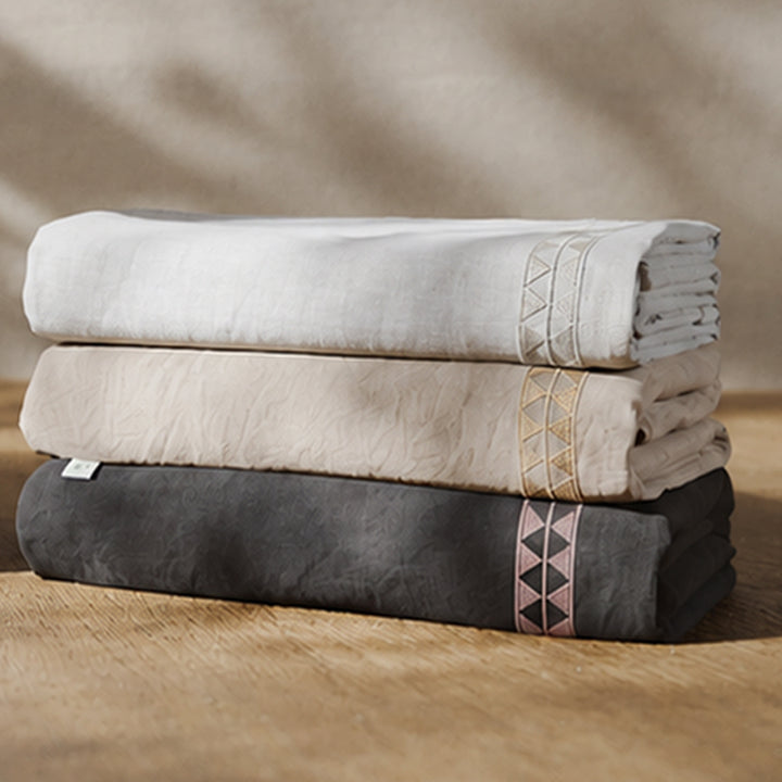 Fundas duvet Alba dobladas en tres tonos, con detalle de bordado geométrico.