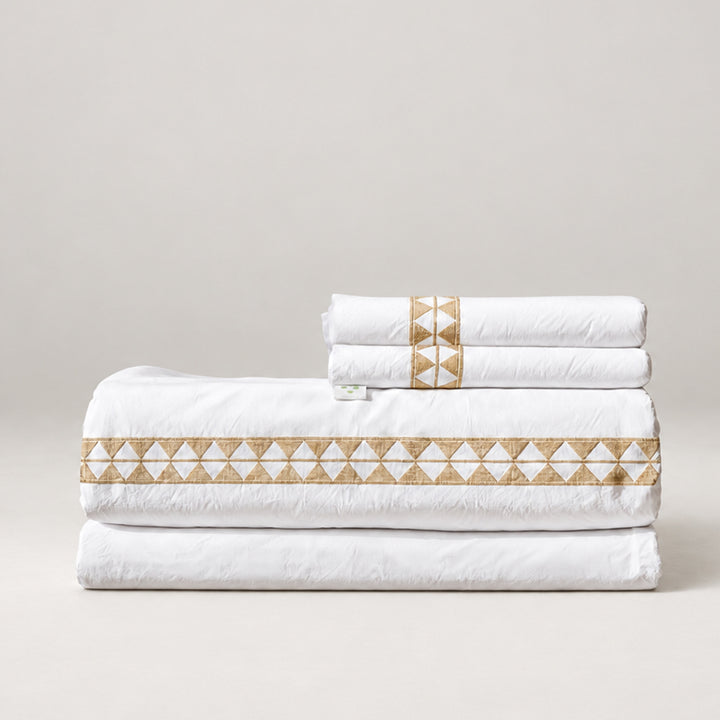 Juego de Sábanas Alba blanco con bordado khaki y fundas de almohada, presentado doblado.