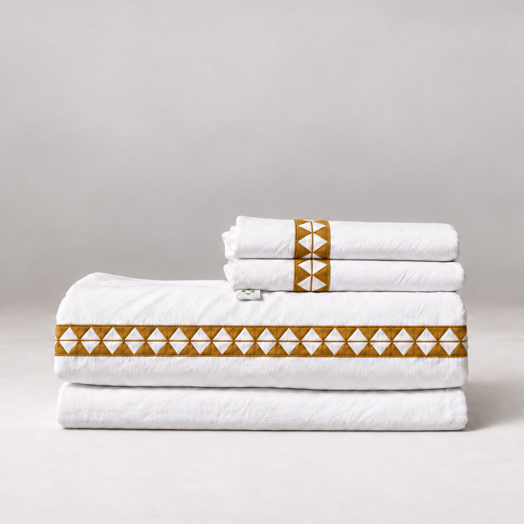 Juego de Sábanas Alba blanco con bordado sunset y fundas de almohada, presentado doblado.