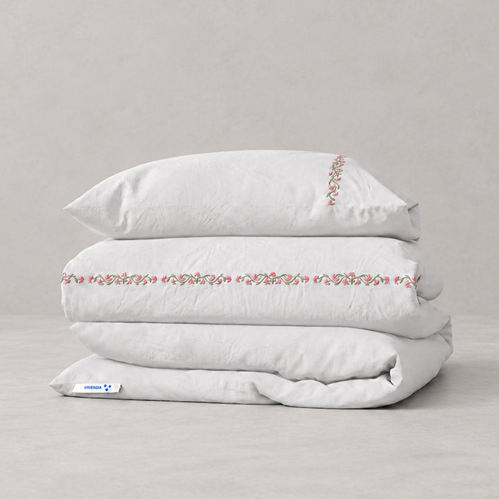 Funda Duvet Chicori de algodón percal blanco con bordado floral Rosa+Laurel y fundas de almohada, presentada doblada.