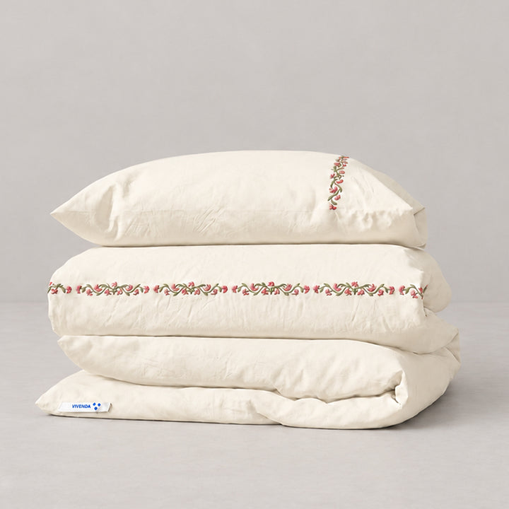 Funda Duvet Chicori de algodón percal crudo con bordado floral Rosa+Laurel y fundas de almohada, presentada doblada.