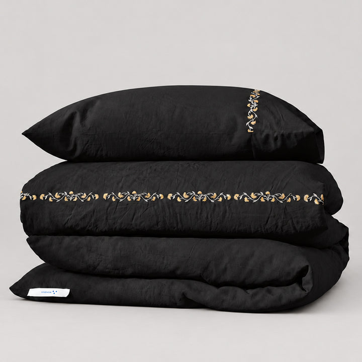 Funda Duvet Chicori de algodón percal noche con bordado floral Crudo+Bruma y fundas de almohada, presentada doblada.