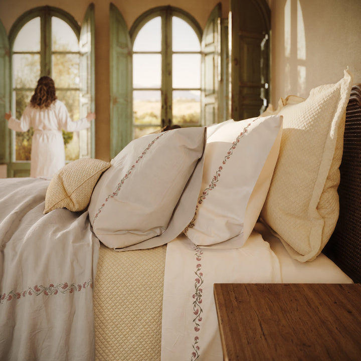 Detalle de la cama Chicori con bordado floral Rosa+Laurel, fundas de almohada y textiles en capas.