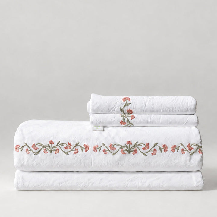 Juego de Sábanas Chicori blanco con bordado floral Rosa+Laurel y fundas de almohada, presentado doblado.