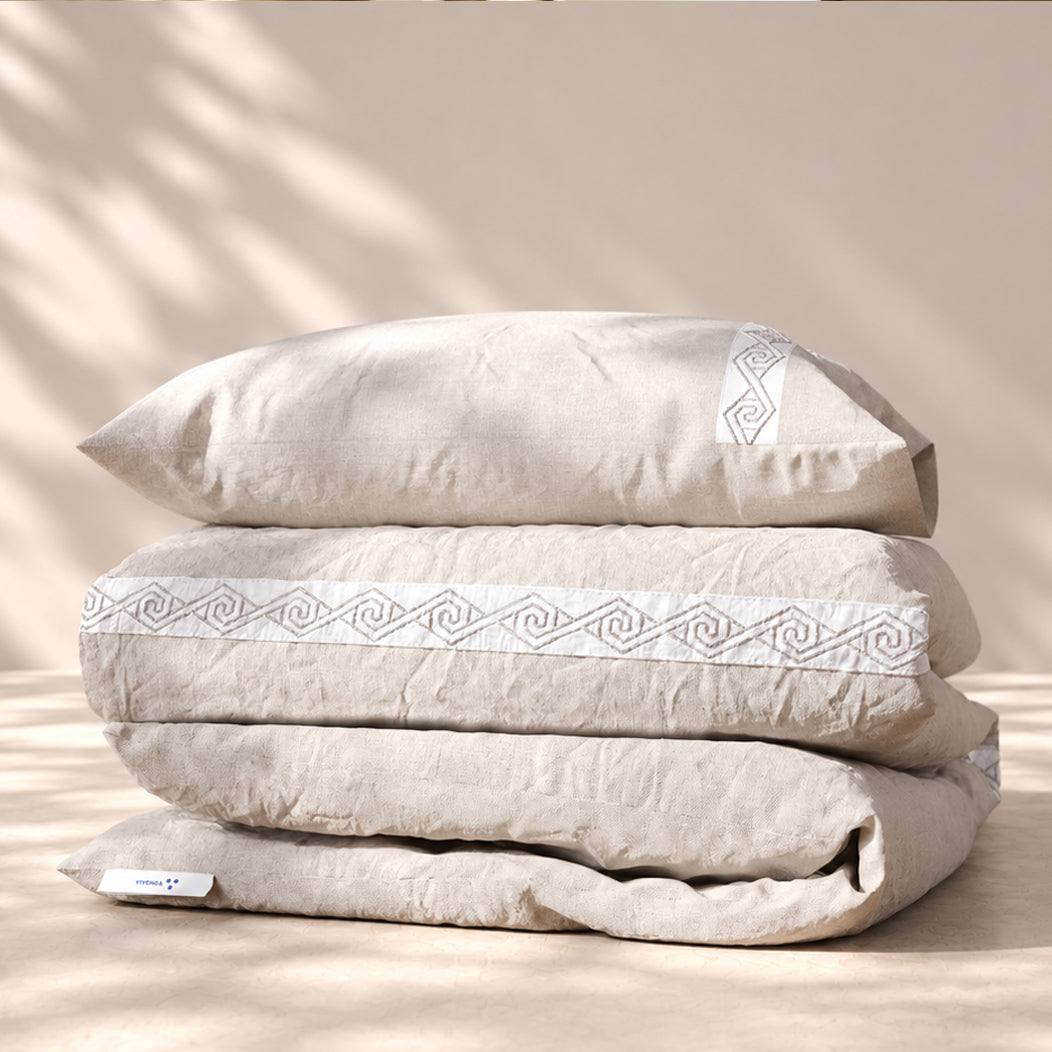 Funda Duvet Senda de lino misto Bruma con tiras blancas bordadas en espiral y fundas de almohada, presentada doblada.