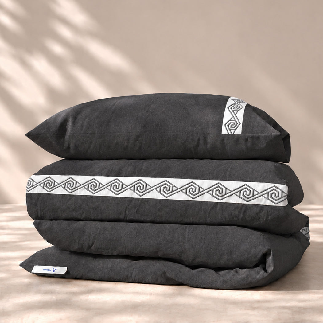 Funda Duvet Senda de lino misto Noche con tiras blancas bordadas en espiral y fundas de almohada, presentada doblada.