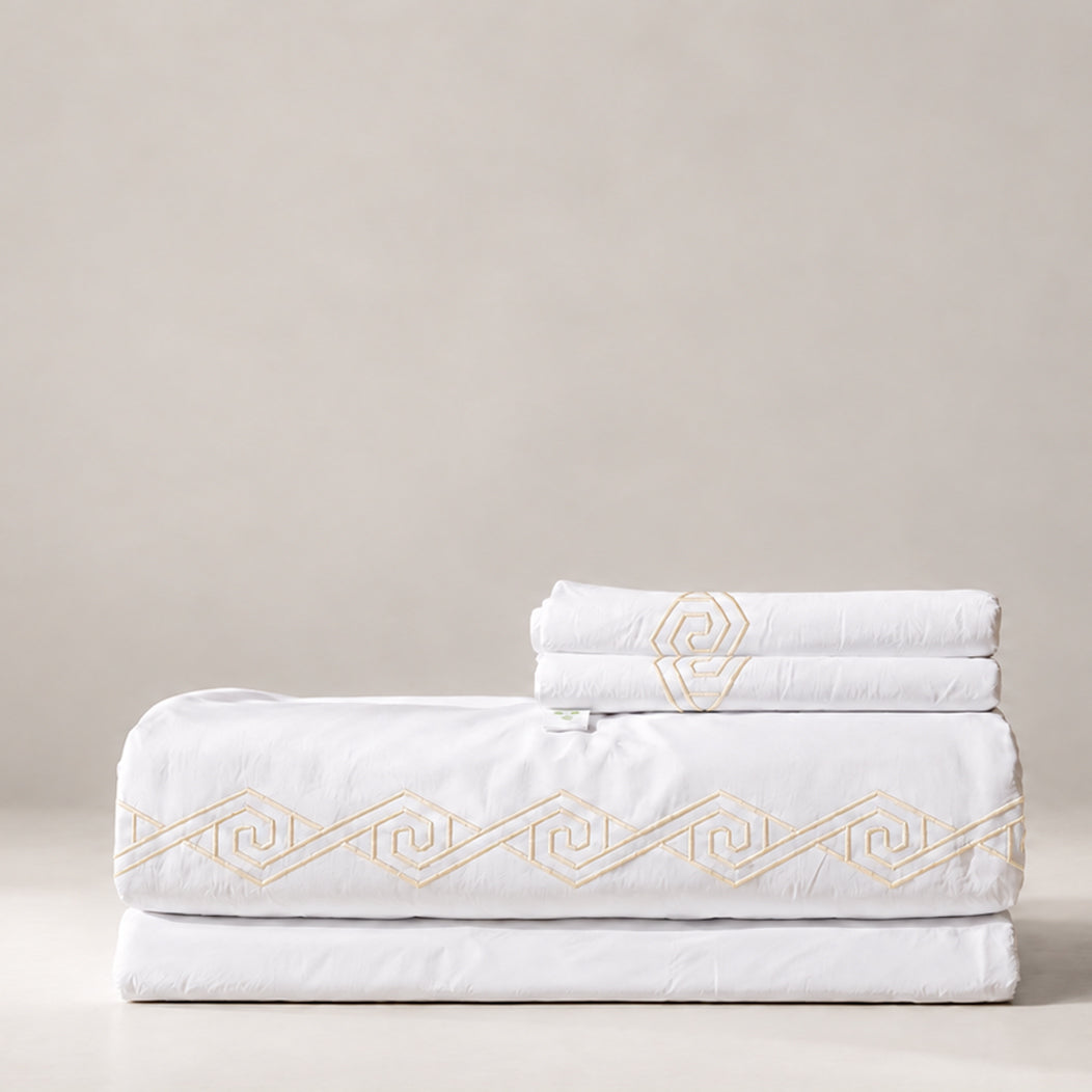 Juego de Sábanas Senda blanco con bordado Crudo en espiral y fundas de almohada, presentado doblado.