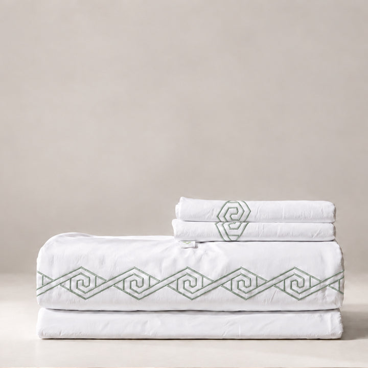 Juego de Sábanas Senda blanco con bordado Laurel en espiral y fundas de almohada, presentado doblado.