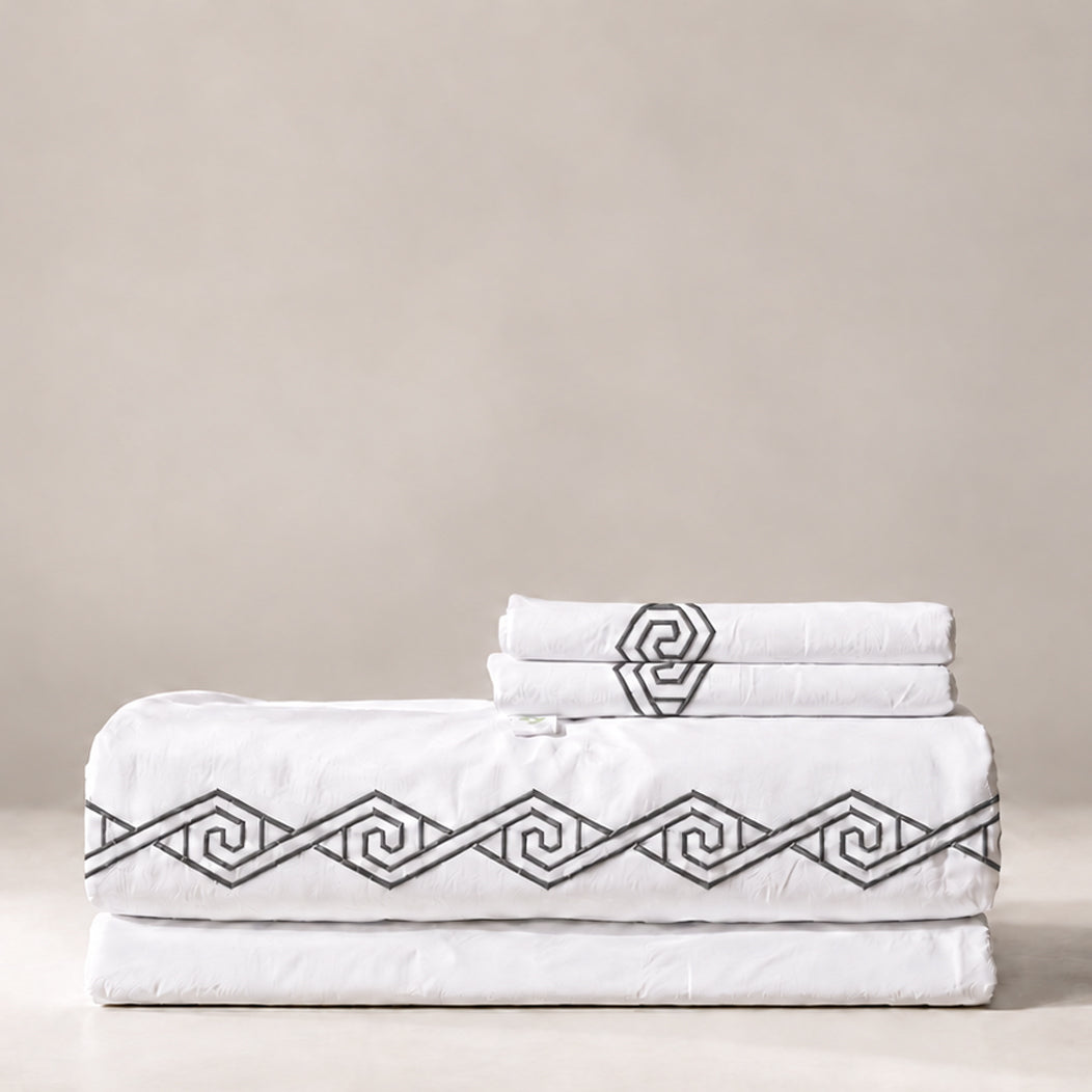 Juego de Sábanas Senda blanco con bordado Noche en espiral y fundas de almohada, presentado doblado.
