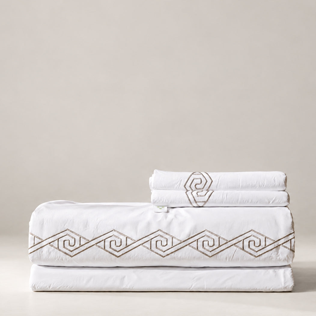 Juego de Sábanas Senda blanco con bordado Olmo en espiral y fundas de almohada, presentado doblado.