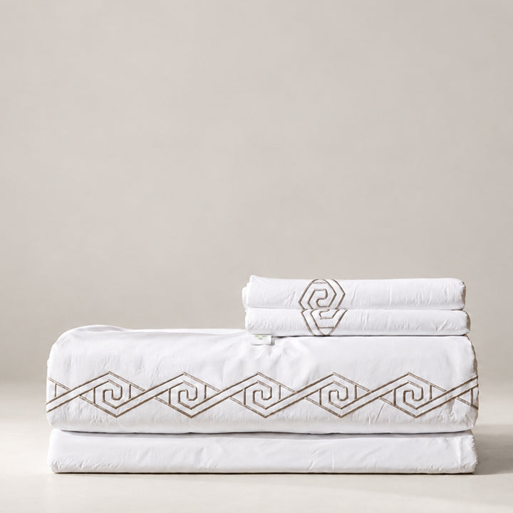 Juego de Sábanas Senda blanco con bordado Olmo en espiral y fundas de almohada, presentado doblado.