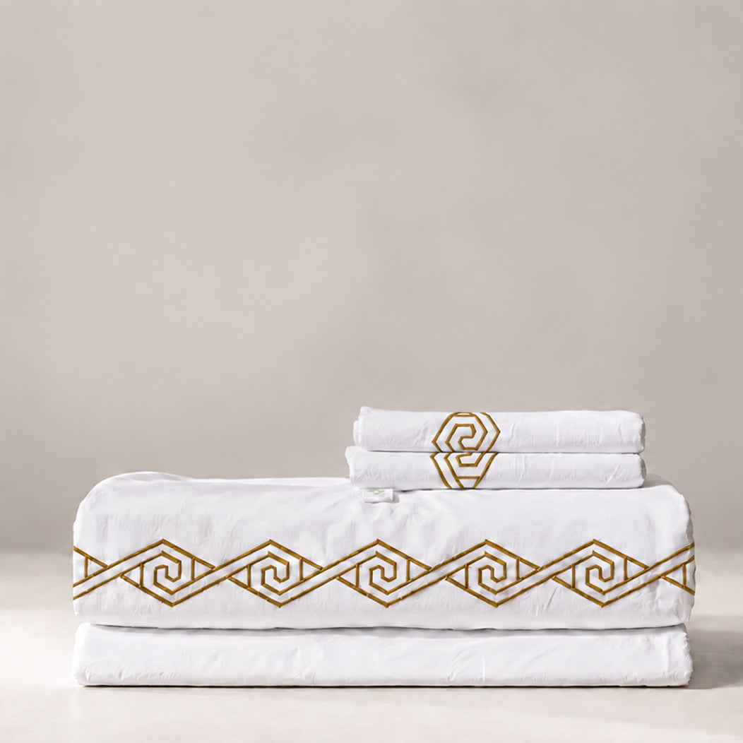 Juego de Sábanas Senda blanco con bordado Sunset en espiral y fundas de almohada, presentado doblado.